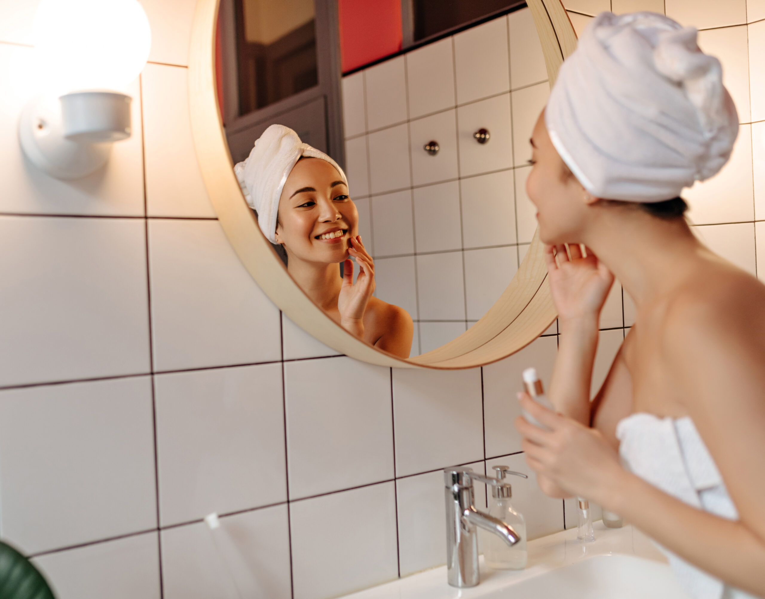 Nice woman makes morning routine and applies cream to cleansed face